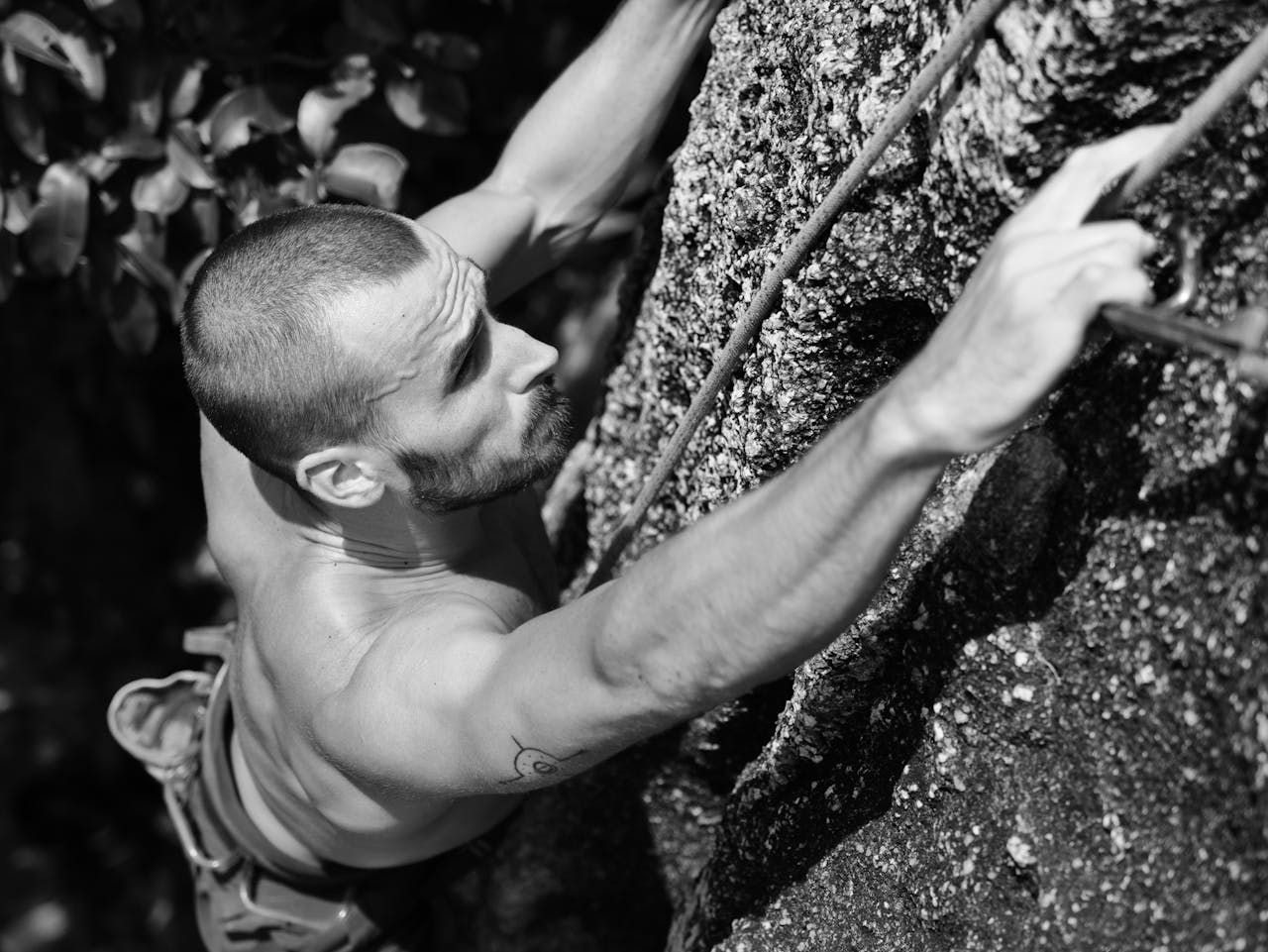 A man with short hair rock climbing on a textured surface in Ko Tao, Thailand.